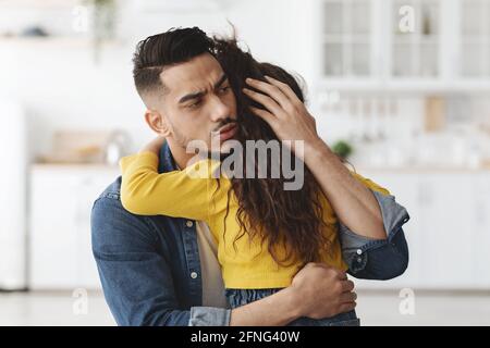Caring Worry Arab Man Hugging Little Daughter, Conforting His Upset Child Stock Photo