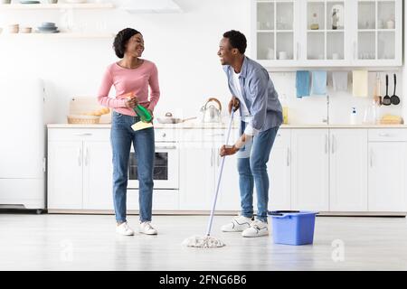 Cheerful black man and woman having fun while cleaning kitchen Stock Photo