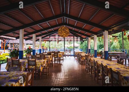 many wooden dining tables arranged on empty roofed terrace in tropical resort in daylight Stock Photo