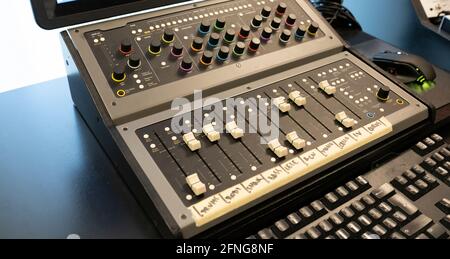 Modern audio mixer with button control panel against computer keyboard on table in sound studio Stock Photo