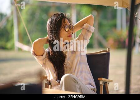 Lovely serious young lady in knitted sweater looking at camera and standing near grey wall Stock Photo