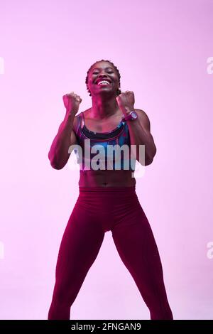 African American sportsWoman in activewear demonstrating win gesture while looking at camera with toothy smile Stock Photo