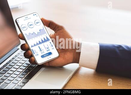 Black manager using mobile phone with trading app Stock Photo