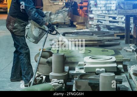 Woman worker sprays special molds for smelting metal parts in foundry workshop. Stock Photo