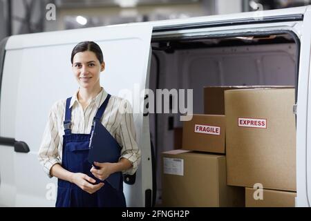Portrait of young woman in uniform smiling at camera standing near the lorry she working in delivery service Stock Photo