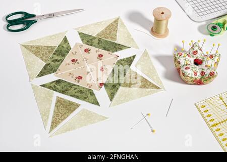 Pieces of fabric laid out in the shape of a patchwork block, sewing and quilting accessories. Stock Photo