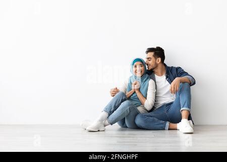 Joyful woman in hijab sitting on floor with her husband Stock Photo