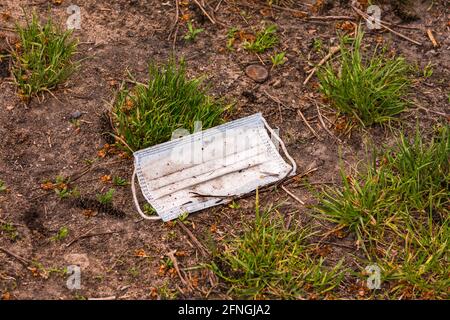 A surgical mask lost in the COVID-19 pandemic pollutes the environment in a field Stock Photo