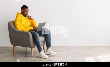 African American Man Using Laptop Thinking Working Online, Gray Background Stock Photo