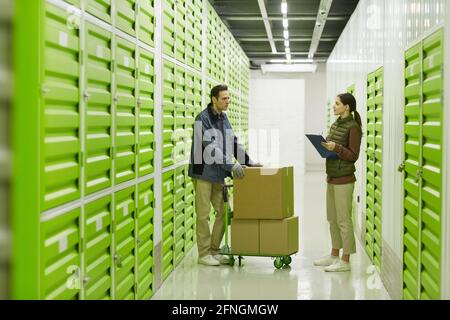 Woman talking to her colleague while they standing in storage Stock Photo