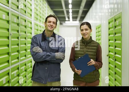 Portrait of two workers smiling at camera while standing in warehouse Stock Photo