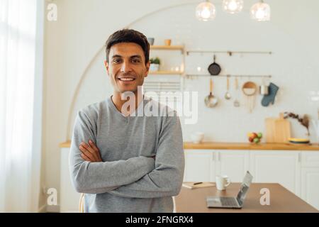 Portrait of smart smiling Caucasian man standing with arms folded at home posing for photos with copy space. Attractive middle age female freelancer looking at camera Stock Photo