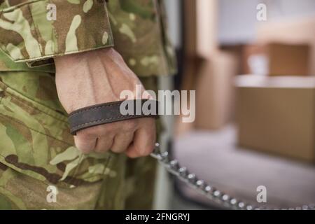 Close-up of military man holding leash in his hand and walking with dog Stock Photo