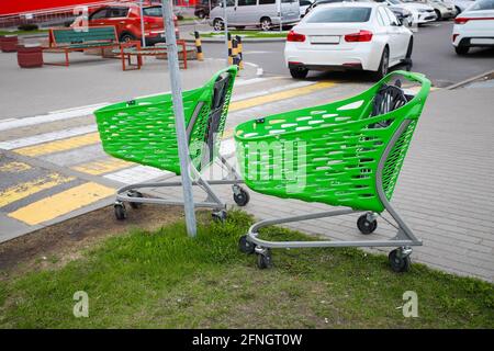 Green shopping carts near a pedestrian crossing in the background of a parking lot for cars. High quality photo Stock Photo