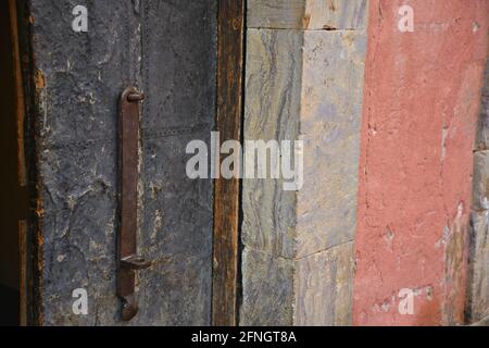 Handcrafted heavy duty wrought iron entrance door with handle against a stone wall in Real de Catorce, San Luis Potosí Mexico. Stock Photo