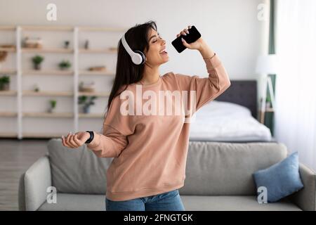 Young woman singing using smartphone as mic Stock Photo