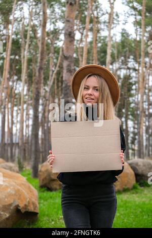 Portrait of caucasian young woman standing with cardboard outdoors. Nature background. Copy space for text Sustainable lifestyle Stock Photo