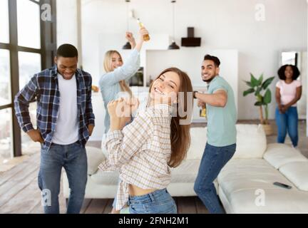 Group of millennial diverse friends having party, dancing and drinking beer, enjoying fun weekend together at home Stock Photo