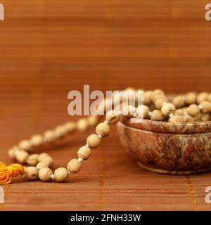 Buddhist prayer beads in a bowl on wooden background. Mindfulness or meditation concept. close up, copy space.
