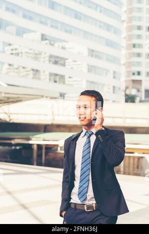 Asian handsome businessman using smart phone walking in the city. Stock Photo