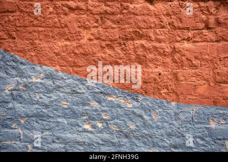 Worn brick wall painted blue and red with curved border Stock Photo