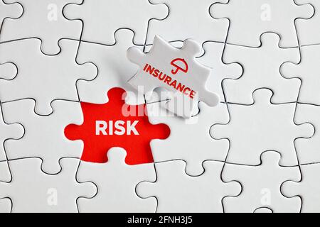 The words risk and insurance on missing puzzle pieces. Reducing or overcoming risks by insurance concept. Stock Photo