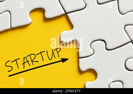 The word startup on yellow background surrounded by puzzle pieces. Business or company startup concept. Stock Photo