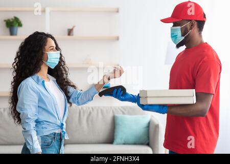 Black delivery man holding pizza box and pos terminal Stock Photo