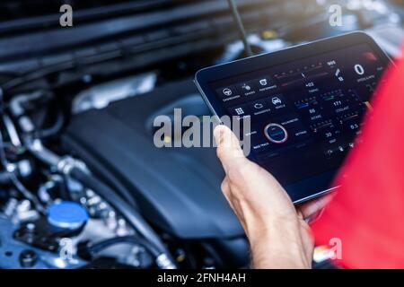 car service mechanic using digital tablet with diagnostics software to check engine condition. vehicle inspection Stock Photo