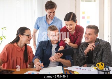 Colleague showing digital tablet to her business friends Stock Photo