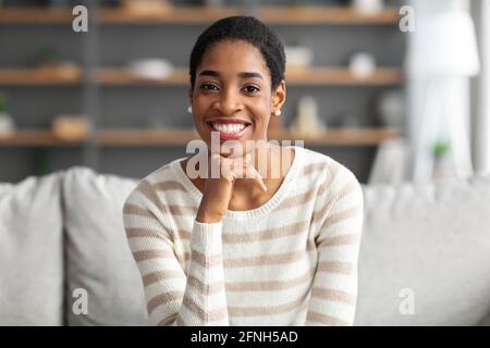 Portrait Of Happy Beautiful Black Female Posing On Couch In Home Interior Stock Photo