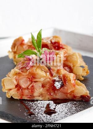 Pie strudel slices on a piece of slate decorated with freshapple flowers and leaves and icing sugar Stock Photo