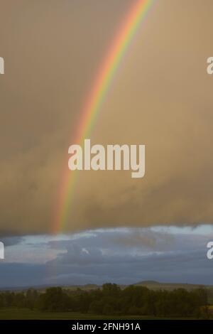 huge rainbow in front of dark clouds Stock Photo