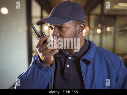 Composition of male security guard using walkie talkie over blurred background Stock Photo