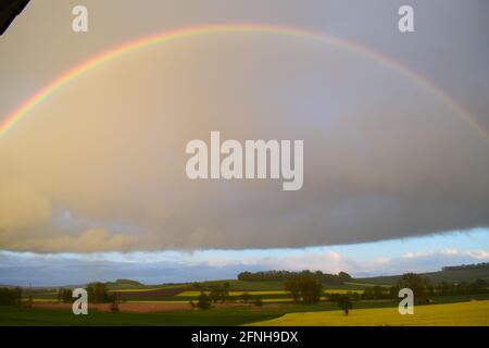 huge rainbow in front of dark clouds Stock Photo