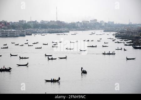 DHAKA, BANGLADESH – MAY : Small wooden boats are seen carrying passengers to cross the Buriganga River in Dhaka, Bangladesh on May 2021. Stock Photo