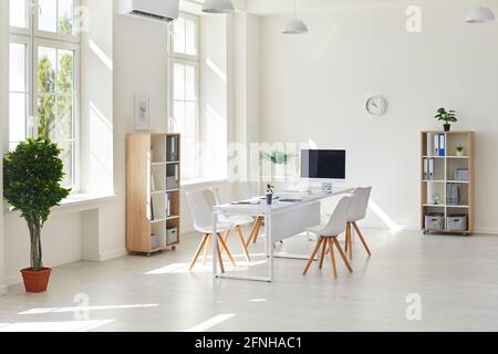 Interior of a modern white business office. Empty light spacious conference room in office with desk, chairs and computer for meetings or online calls Stock Photo