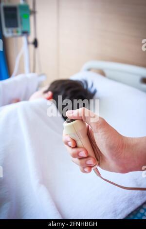 Parent hand pressing emergency nurse call button. Illness child lying on sickbed. Selective focus, emergency nurse call button in focus. Stock Photo