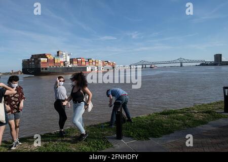 People watch as a massive MSC container ship carrying global cargo passes by on the Mississippi River near New Orleans, Louisiana. Stock Photo