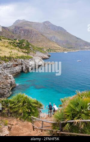 Zingaro Nature Reserve, Trapani, Sicily, Italy. Two hikers admiring view over Cala Marinella from steep coastal path above the Gulf of Castellammare. Stock Photo