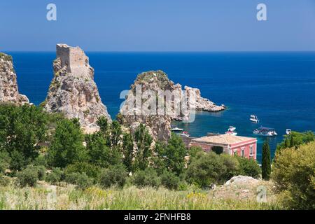 Scopello, Trapani, Sicily, Italy. View over treetops to the Faraglioni, a series of stacks in the Gulf of Castellammare off the Tonnara di Scopello. Stock Photo