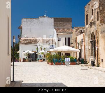 Scopello, Trapani, Sicily, Italy. Quiet pavement cafes in a sunlit corner of Piazza Cetaria at the centre of the village. Stock Photo