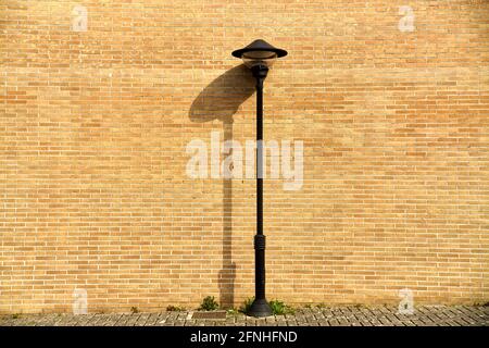 Lonely black lamppost on yellow bricks background Stock Photo