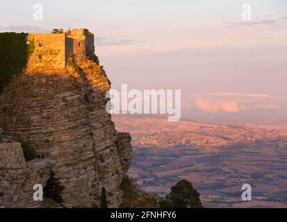 Erice, Trapani, Sicily, Italy. The clifftop Castello di Venere lit by the setting sun, warm evening light on agricultural land beyond. Stock Photo