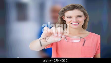 Composition of woman holding reading glasses on blurred medical background Stock Photo