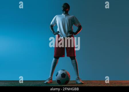 Young African soccer football player posing isolated on blue background in neon light Stock Photo