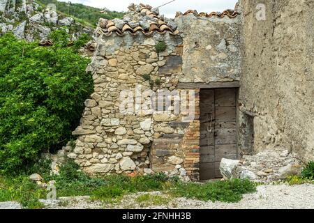 Old ruined and abandoned house with wooden door. Potted by plants. Corvara, province of Pescara, Abruzzo, Italy, Europe Stock Photo