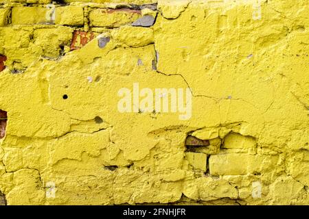 Fragment of an old wall with rough plaster and bright yellow brickwork Stock Photo