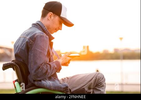 young disabled man in wheelchair walking park Stock Photo