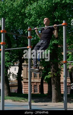 athletic young man with artificial leg working out on a bars Stock Photo